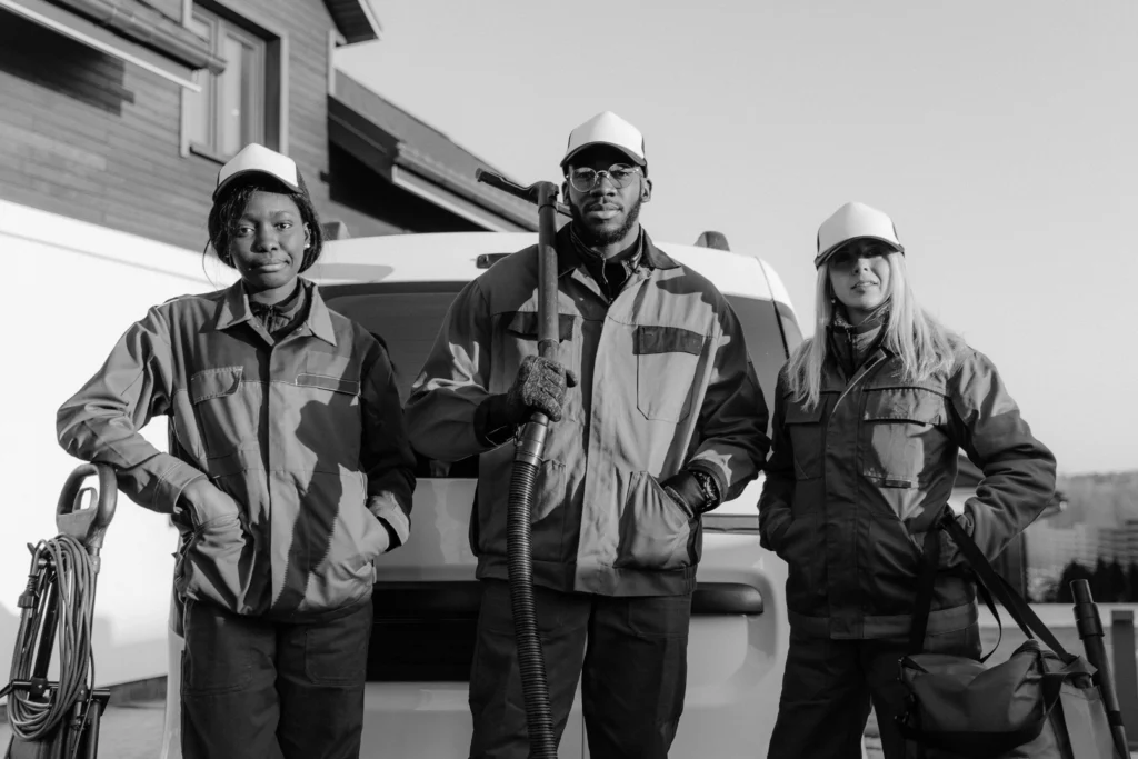 picture of a black and white portrait of three cleaners standing in front of a van with their equipment