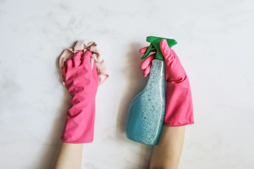 picture-of-a-pair-of-hands-in-pink-rubber-gloves-using-a-cloth-and-a-spray-bottle-to-clean-a-white-marble-surface