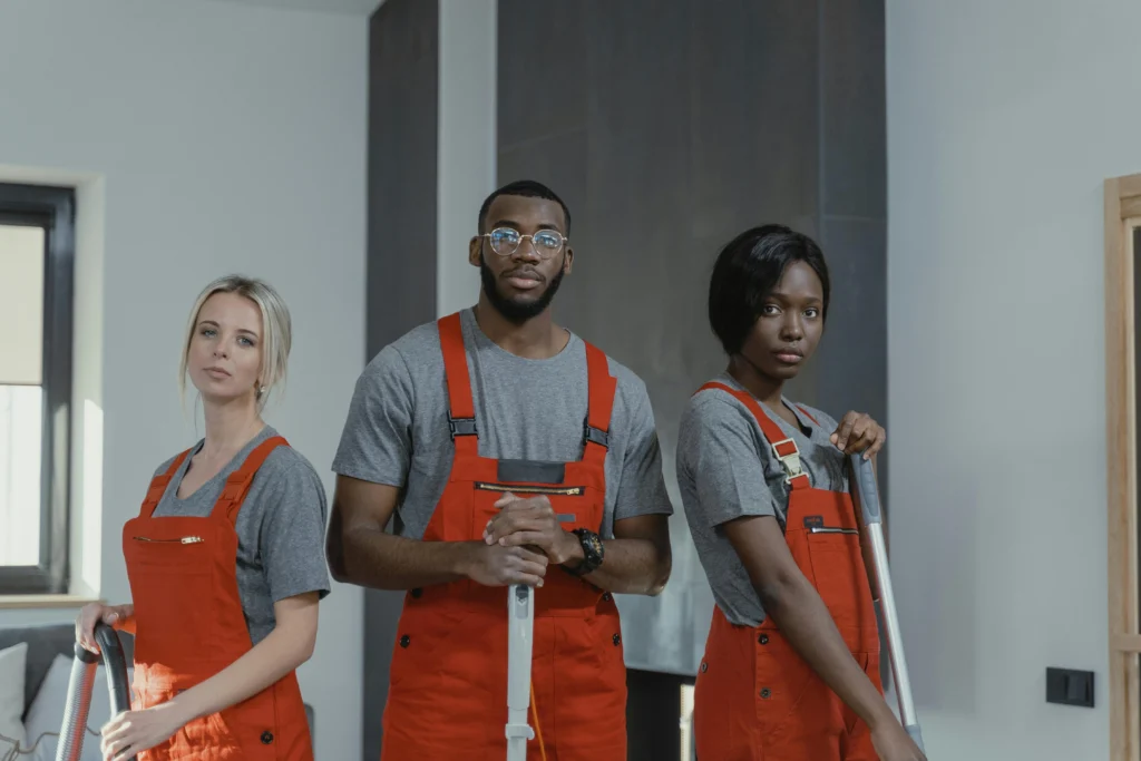 picture of a team of three professional cleaners in orange overalls posing with their equipment performing cleaning services in birmingham