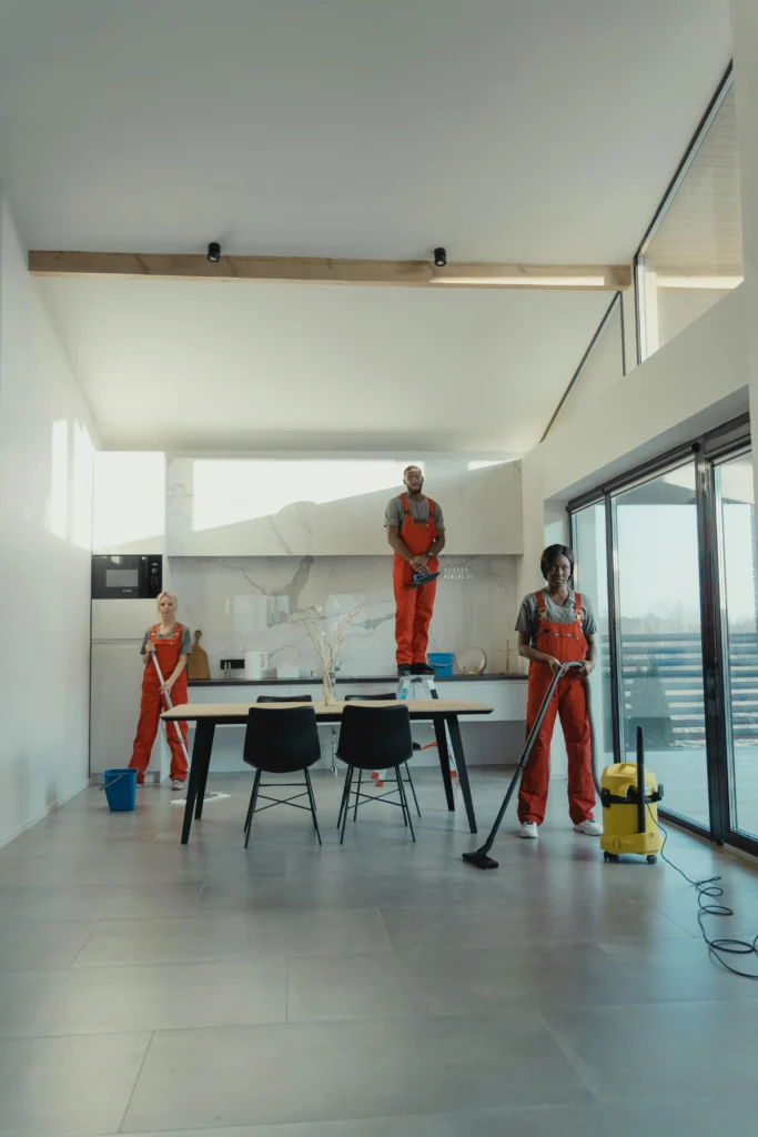 picture-of-three-people-cleaning-team-in-red-uniforms-performing-an-end-of-tenancy-cleaning-bristol-service-using-a-mop-vacuum-and-step-ladder-to-clean-a-modern-kitchen