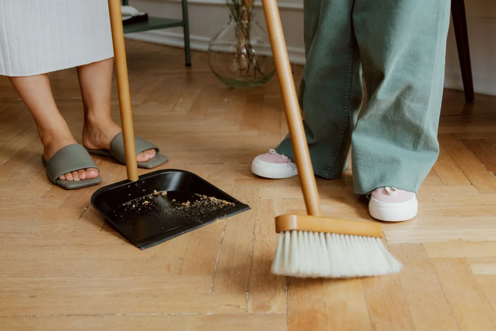 Picture of a person sweeping a wooden floor.