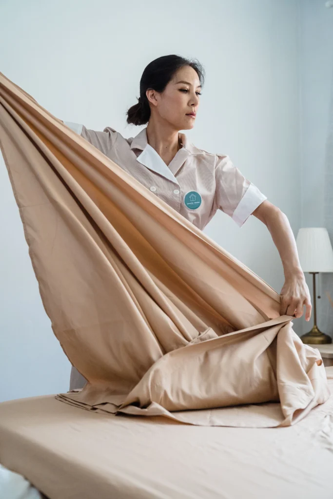 Picture of a cleaner in a uniform making a bed